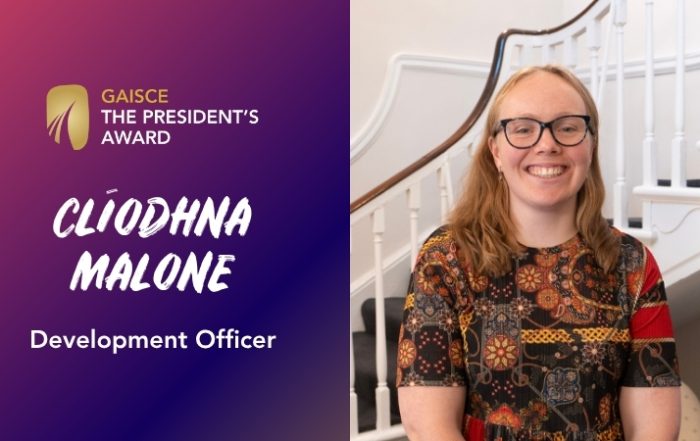 gaisce logo (gold medal with 3 arches of increasing size at bottom), clíodhna malone, development officer, with an image of clíodhna. she has blonde hair, glasses, smiling bright and is wearing a shirt with splashes of orange, red, black.